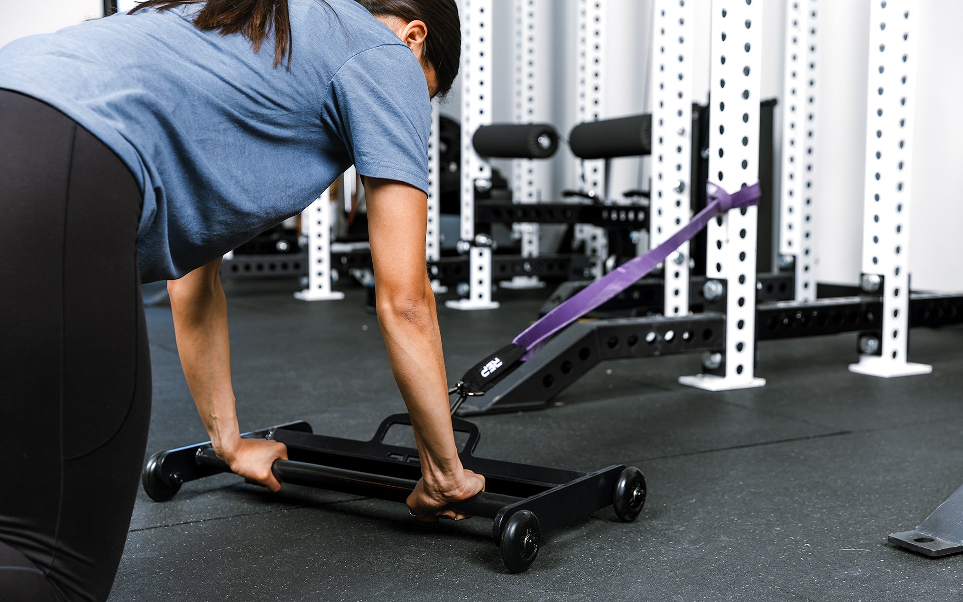 Athlete using glute ham roller with bands attached to a rack for ab exercises