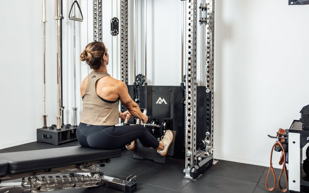 An athlete performing a low cable row on the Wall-Mounted Ares™ 2.0 while seated on a REP BlackWing™ bench